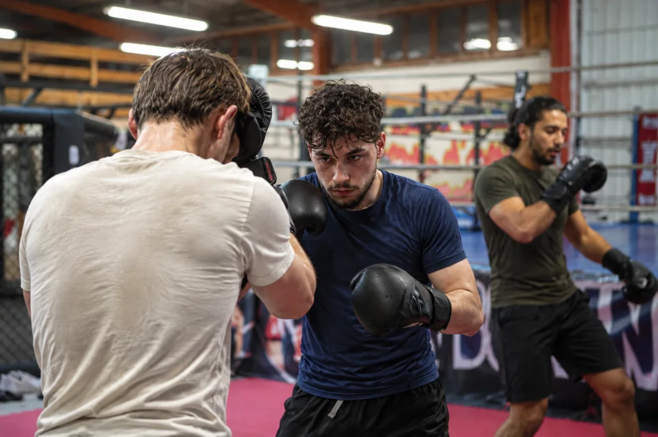 Club de boxe proche de Blagnac : trois pratiquants Boxing Center en garde, en tenues crème, marine et olive.